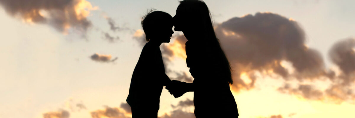 Silhouette of mother kissing her son on the head