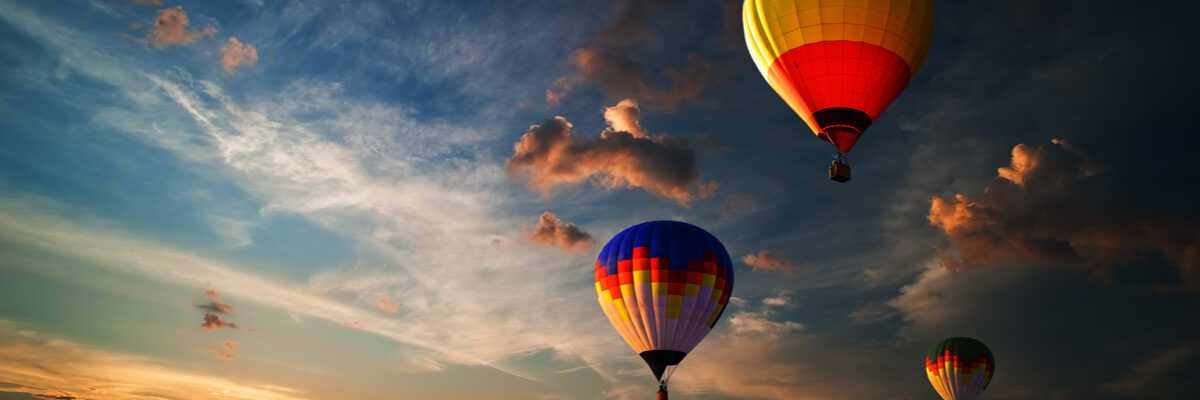 Three colourful hot air balloons flying at sunrise