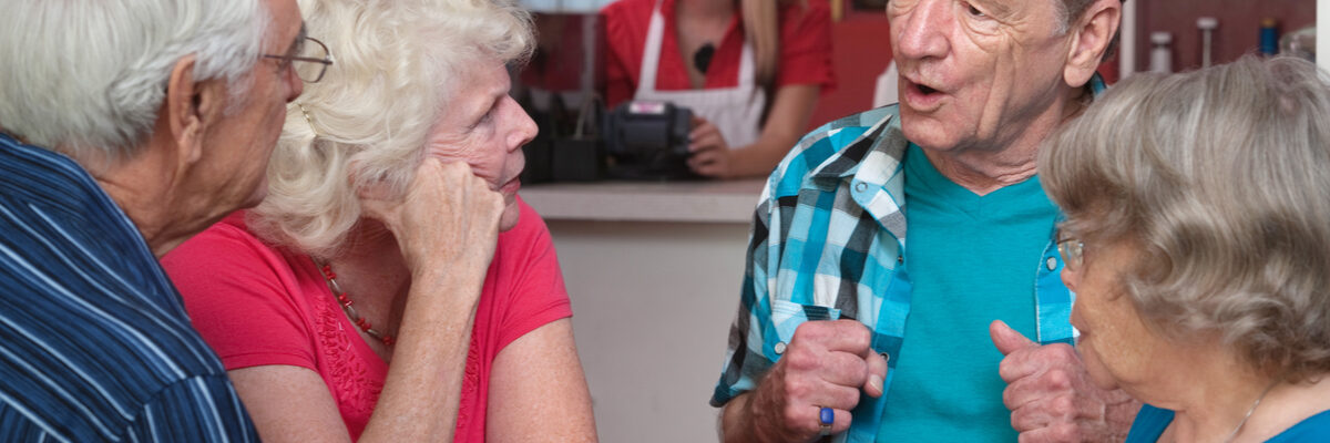 Four senior adults drinking coffee in a cafe